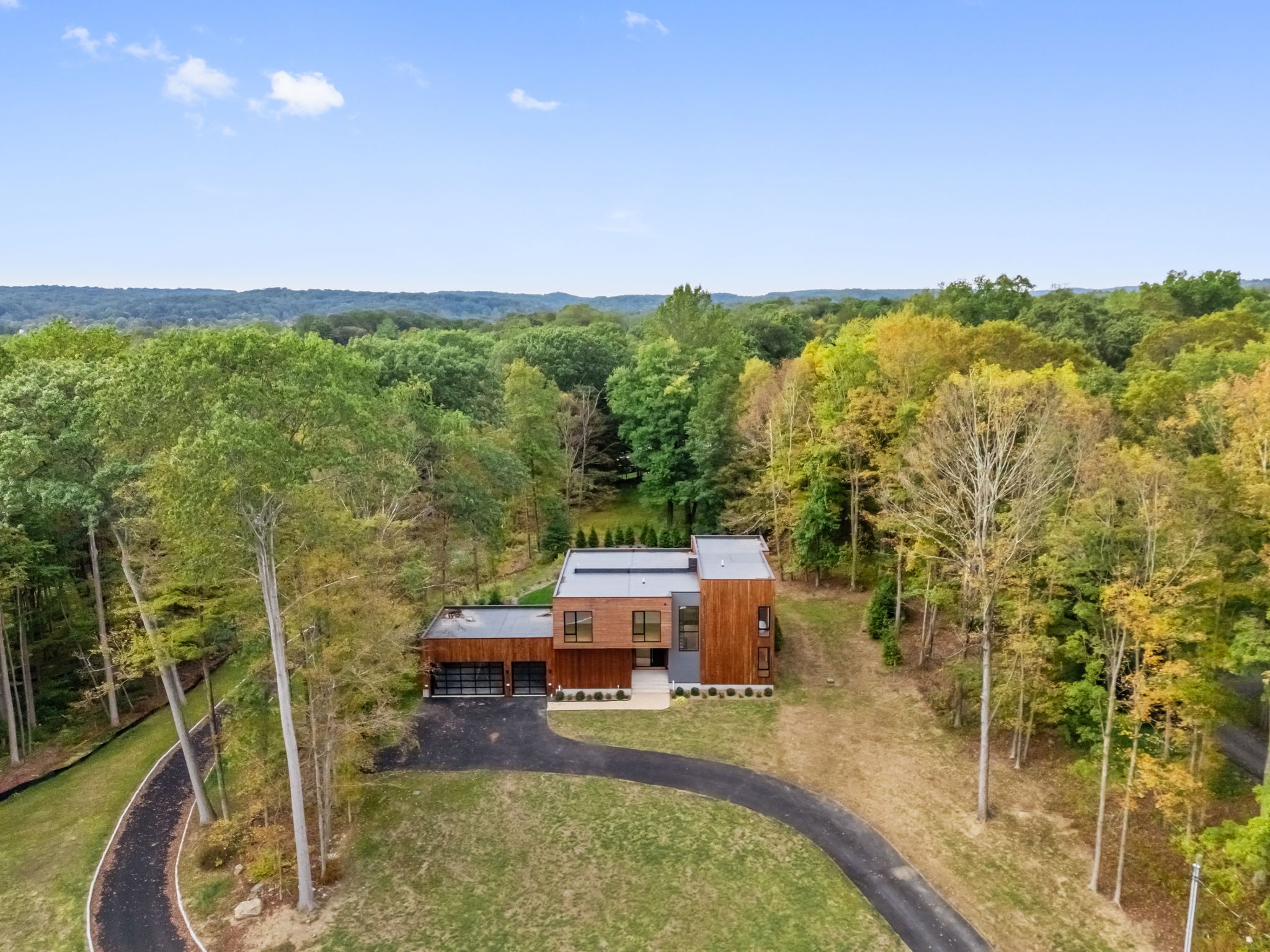 East Lane, Armonk, NY: aerial view of a cedar residence set in a clearing of autumn woodland